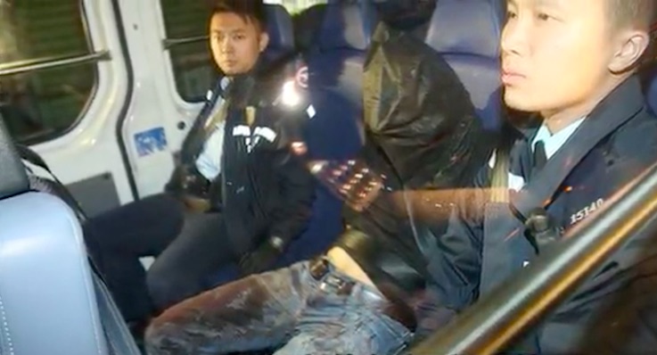 A 37-year-old man surnamed Tse is photographed in the back of a police van wearing blood-stained jeans after stabbing his girlfriend with a kitchen knife following a fight. Screengrab via Apple Daily video.