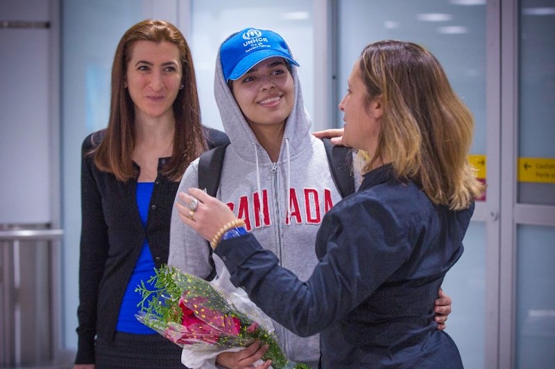 Saudi teenager Rahaf Mohammed al-Qunun (centre, blue cap) is welcomed by Canadian Minister for Foreign Affairs Chrystia Freeland (right) as she arrives at Pearson International airport in Toronto, Ontario, on January 12, 2019. The woman on the left is Saba Abbas from COSTI immigrant services. (Photo by Lars Hagberg / AFP)