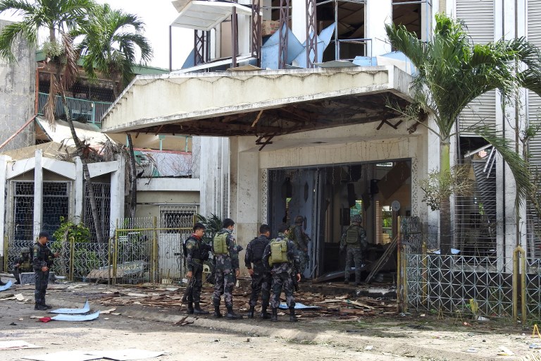 Policemen and soldiers stand outside bomb-hit church in Jolo, Sulu province on the southern island of Mindanao, on January 27, 2019. (Photo: Nickee Butlangan, AFP)