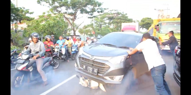 Police officers in Surabaya attempting to secure a vehicle containing  former legislator Wisnu Wardhana after it got stuck on a motorcycle while trying to flee. Credit: Dokumentasi Kejaksaan Negeri Surabaya