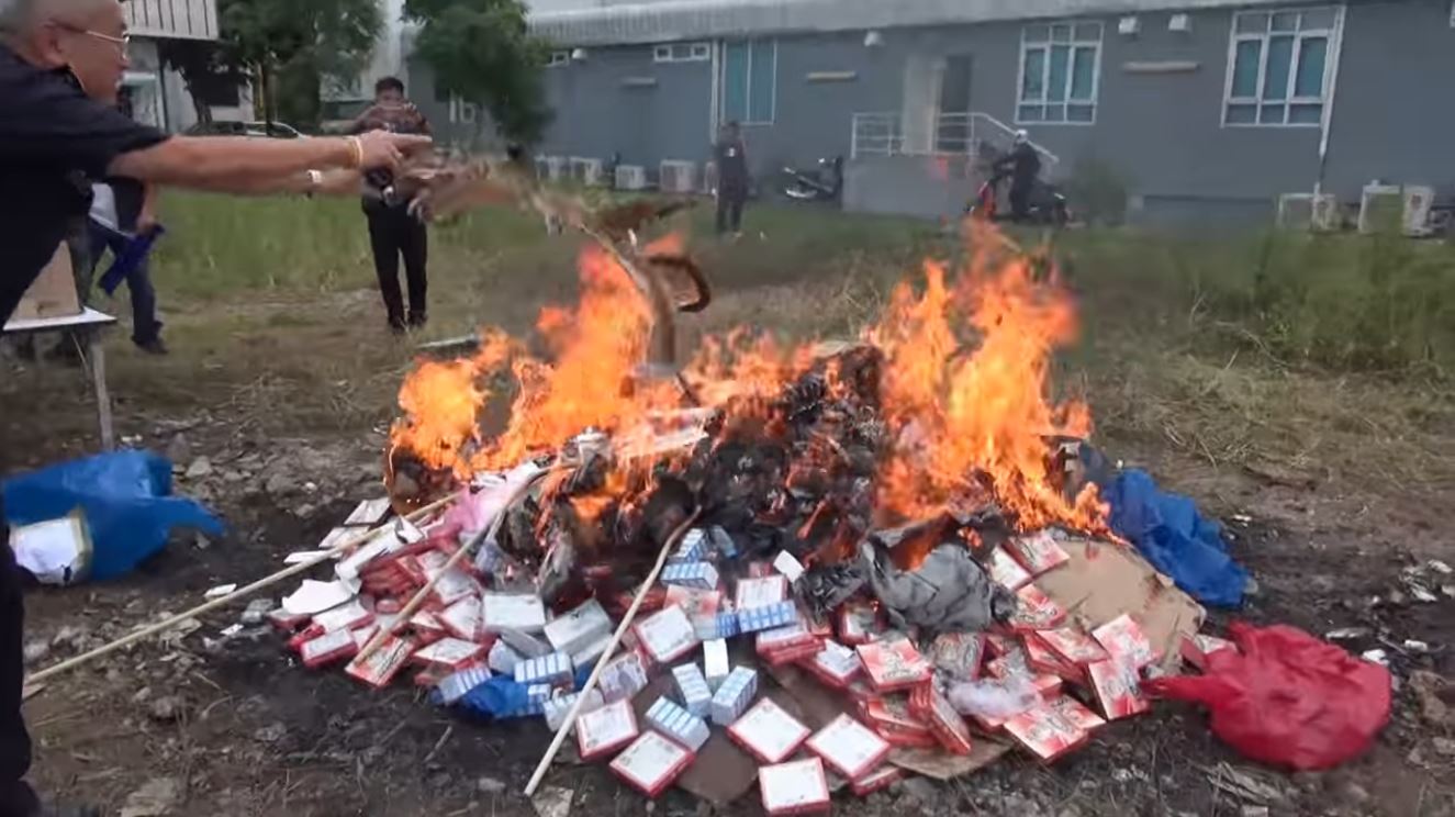 Officials appeared amused when filmed throwing products in an open-air bonfire.Screenshot: Khaosod TV 