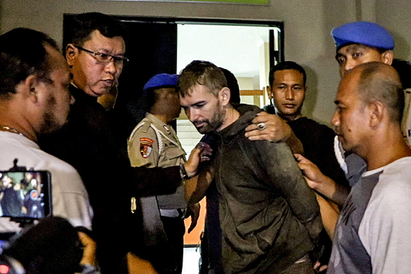 Frenchman Felix Dorfin (C) is under escort after escaping from jail in Mataram on the holiday island of Lombok on February 2, 2019, helped by a police officer who received a US$1,000 bribe from him. (Photo by PIKONG / AFP)