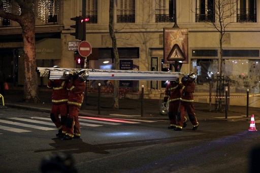 Firefighters carry a ladder near a building that caught fire in Rue Erlanger in Paris. Photo: Geoffroy Van Der Hasselt/AFP)