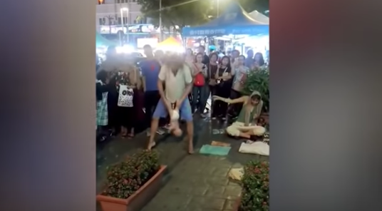 A Russian busker is seen swinging a baby by its ankles as part of a street performance act in Kuala Lumpur. Screen grab: YouTube