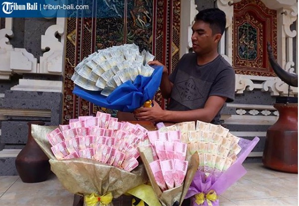 Astika proudly displays his banknote bouquets. Photo courtesy of Tribun Bali