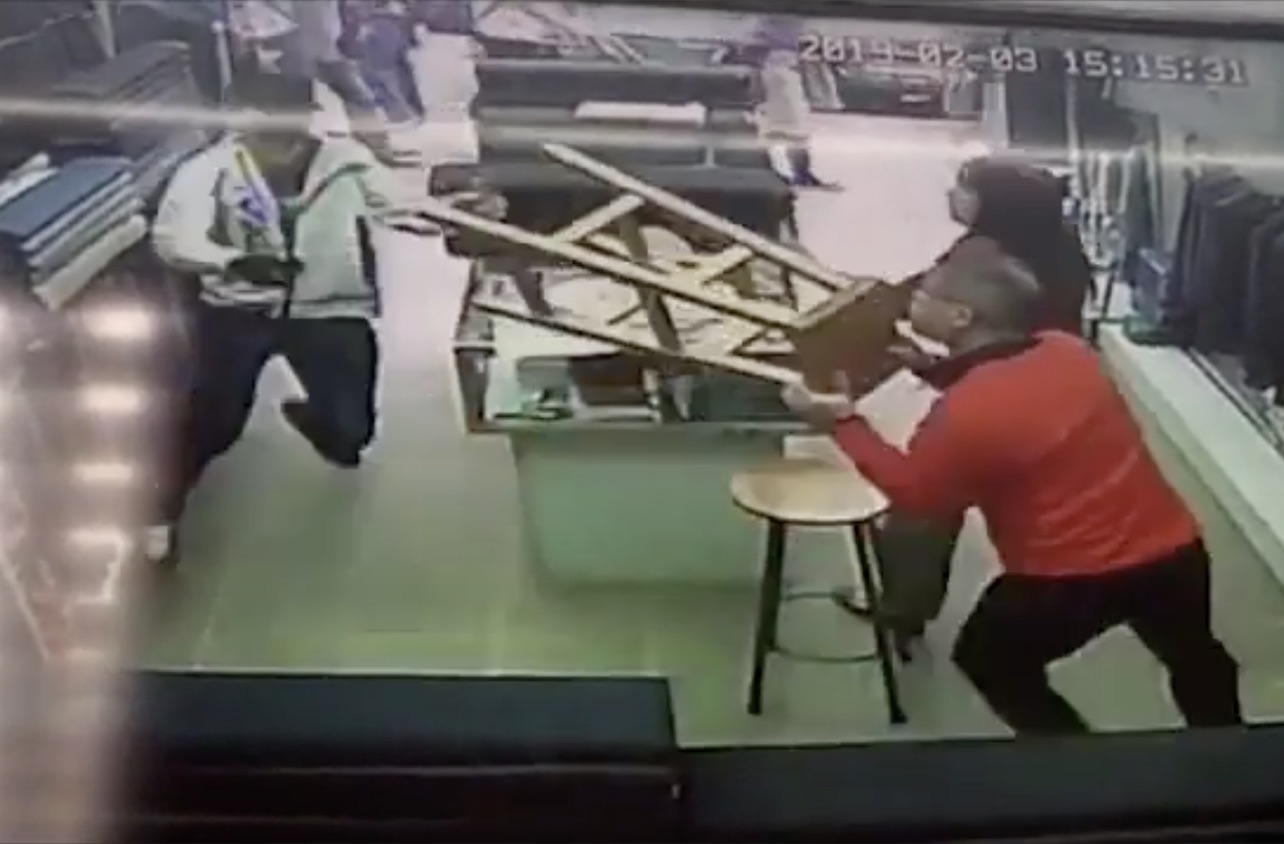 CCTV footage captures the moment a masked men runs into a tailor store tries to attack the owner with a 20-inch knife. The store’s owner tries to defend himself with a stool. Screengrab via Apple Daily video.