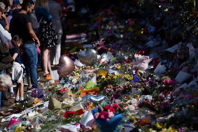 Floral tributes to those who were gunned down at the two mosques are seen against a wall bordering the Botanical Garden in Christchurch on March 19, 2019. (Photo by Marty MELVILLE / AFP)