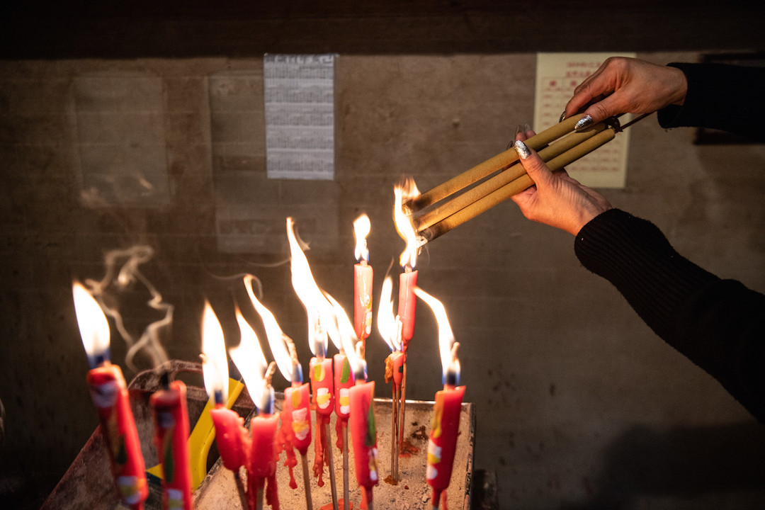 The author’s mother lights incense during their visit to Hong Kong’s Man Mo Temple.