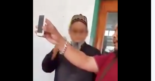 An angry parent confronts the teacher, showing allegedly incriminating photos on phone via Twitter
