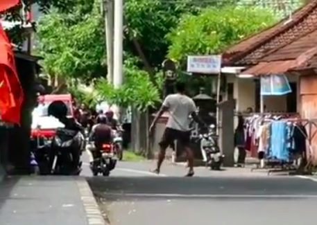 The man was filmed staggering all over Jl. Pulau Batanta in Denpasar whilst wildly flailing a sword around in one hand. Photo: Still from a video posted by @denpasar.viral