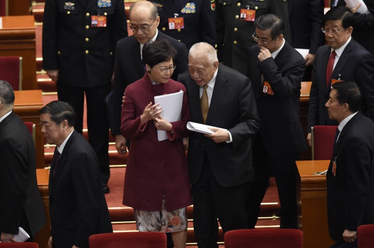 Hong Kong Chief Executive Carrie Lam (center) talks with former Hong Kong Chief Executive Tung Chee-hwa after the opening session of the National People’s Congress in Beijing earlier this month. Photo via AFP.