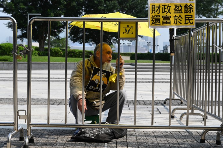 A pro-democracy protester sits outside the Legislative Council before a speech on the 2019 budget in February. Photo via AFP.