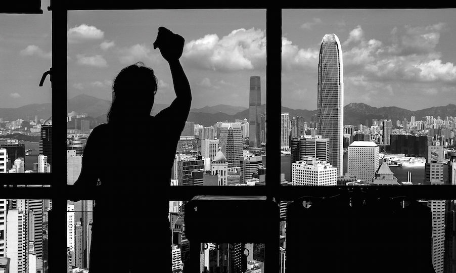A domestic worker cleans a window in Hong Kong. Photo courtesy of Xyza Cruz Bacani.