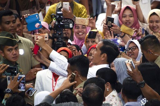 Indonesia’s President Joko Widodo (C) taking a selfie with his supporters during an election campaign stop in  Central Java province. Photo by JUNI KRISWANTO / AFP)