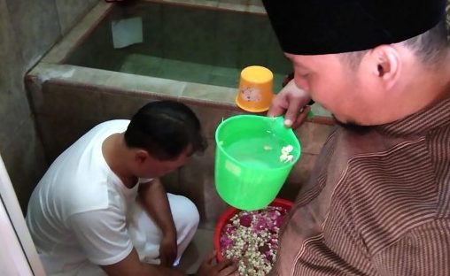 This picture taken on April 23, 2019 shows political hopeful Yayat Abdurahman (L) being doused with water as part of a traditional cleansing ritual by a cleric at an Islamic healing centre in Cirebon. – Political hopeful Yayat Abdurahman bet that he would be a winner among some 245,000 candidates in Indonesia’s huge election last week, but his dreams of public office are fading fast as the votes get tallied. (Photo by Andri Sulistyo / AFP) / 