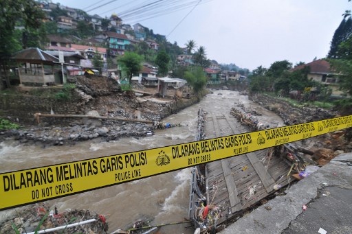 A police line is placed at a damaged bridge following torrential rain in Bogor, West Java on April 28, 2019. – Landslides and floods are common in Indonesia, especially during the monsoon season between October and April, when rains lash the vast Southeast Asian archipelago. (Photo by RANGGA FIRMANSYAH / AFP)