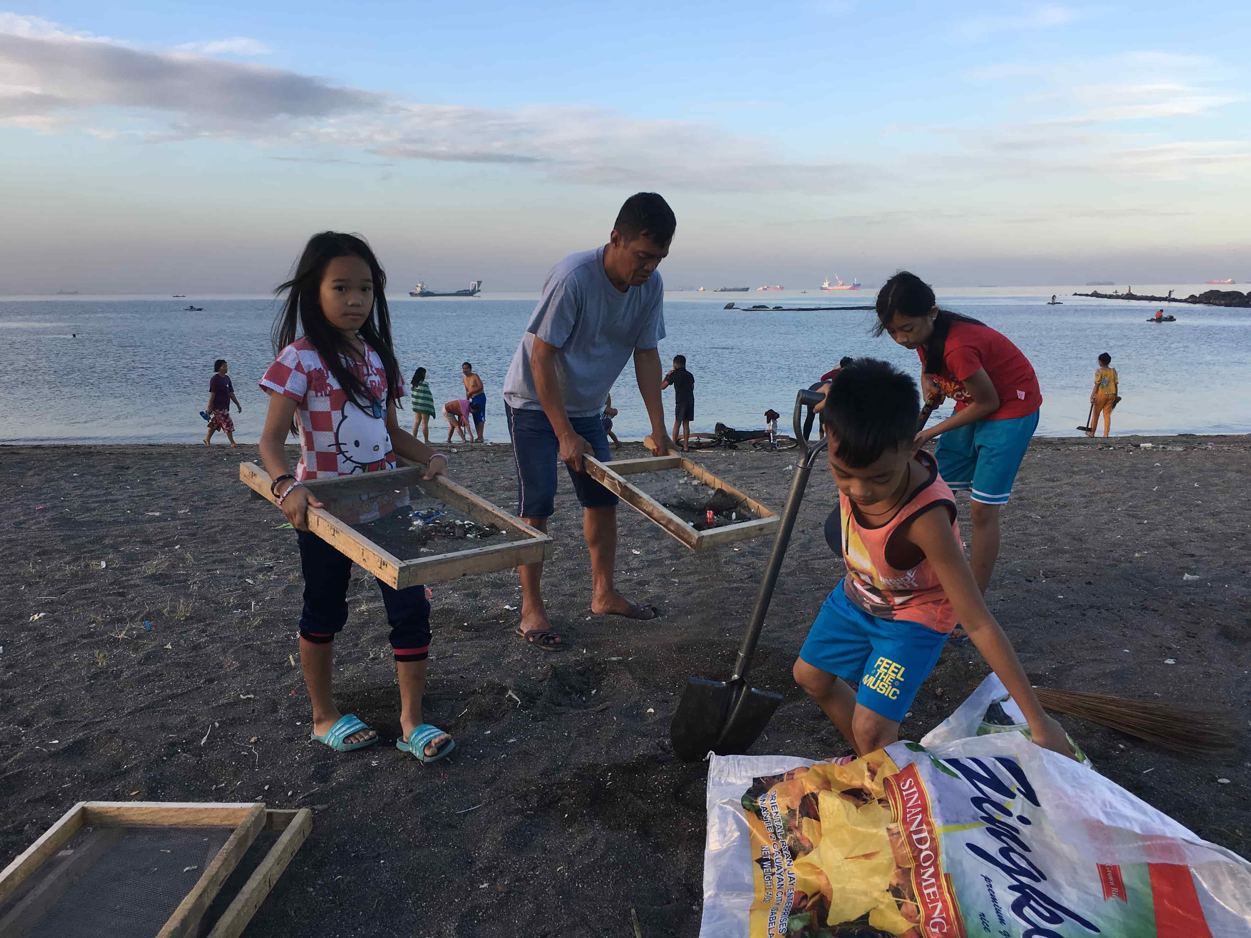 Baseco residents picking up pieces of plastic. (Photo: Therese Reyes/Coconuts)