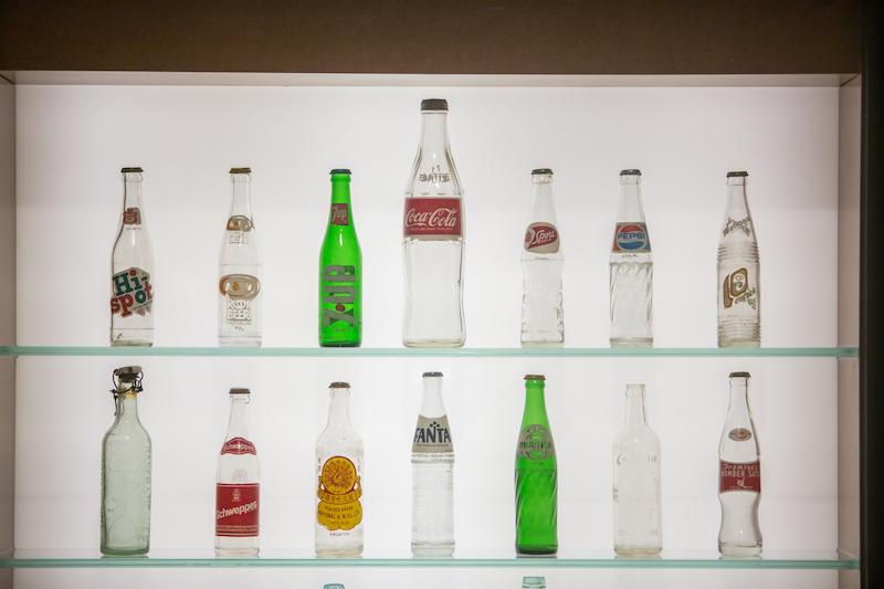 Wall showcase of bottles from local and international brands across the '60s-'70s. Photo: National Museum of Singapore