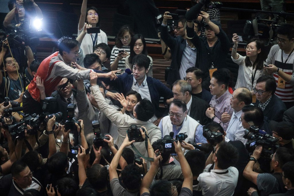 Hong Kong pro-Beijing lawmaker Abraham Shek (centre R-in white vest) is escorted from a legislative meeting after scuffles broke out between pro-Beijing and pro-democracy lawmakers in the Legislative Council (LegCo) in Hong Kong on May 11, 2019. – Anger over Hong Kong’s controversial plans to allow extraditions to the Chinese mainland boiled over in the city’s legislature on May 11 as rival lawmakers scuffled with each other in chaotic scenes. (Photo by STR / AFP)