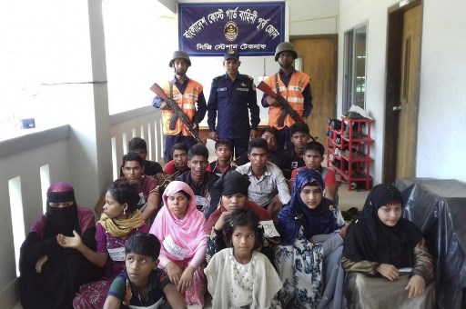 Bangladesh Coast Guard pose for a photo with rescued Rohingya refugees in Teknaf on May 18, 2019. – Bangladesh authorities prevented 84 Rohingya refugees from Myanmar from attempting a perilous boat journey to Malaysia, officials said on May 18. (Photo by STR / AFP)