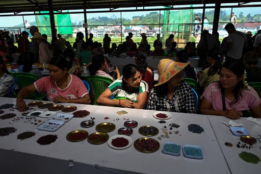 This photo taken on May 17, 2019 shows sellers trading rubies and gemstones at the gems market in Mogok town, north of Mandalay. – Burrowing deep underground, thousands of informal miners risk their lives to find gleaming red gems as a law change spurs opportunity in Myanmar’s “land of rubies”. (Photo by Ye Aung THU / AFP)