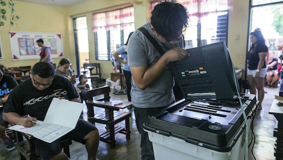 A technician checks a malfunctioning ballot-counting machine. Photo: Fernando Sepe Jr./ABS-CBN News