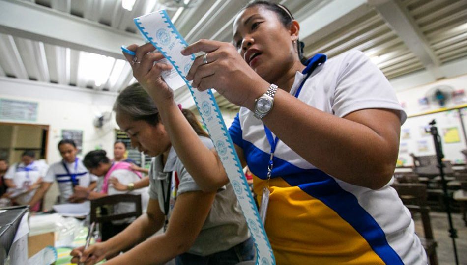 A teacher looks at the receipt printed from a vote-counting machine in a school in Quezon City. Photo: Gigie Cruz/ABS-CBN News