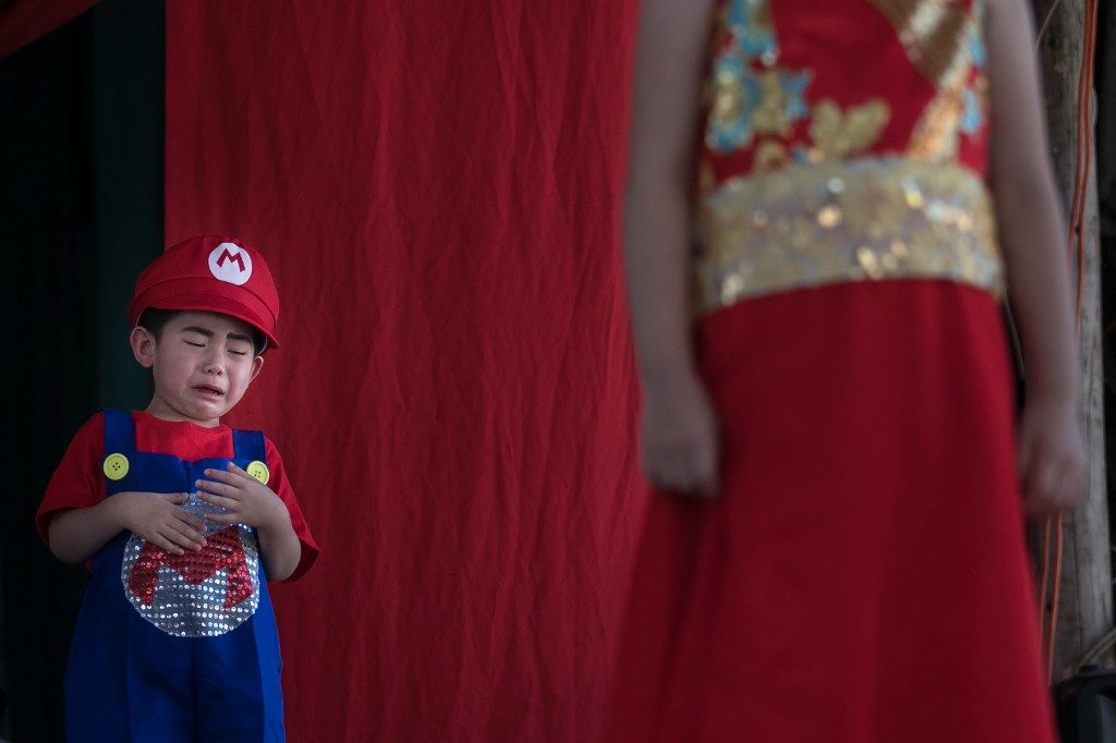 A child, dressed as Super Mario and standing on a pedestal held above worshipers, cries during the Cheung Chau Bun Festival on Sunday. Apparently the so-called 'generic kids' don't have it all bad. Photo via AFP.