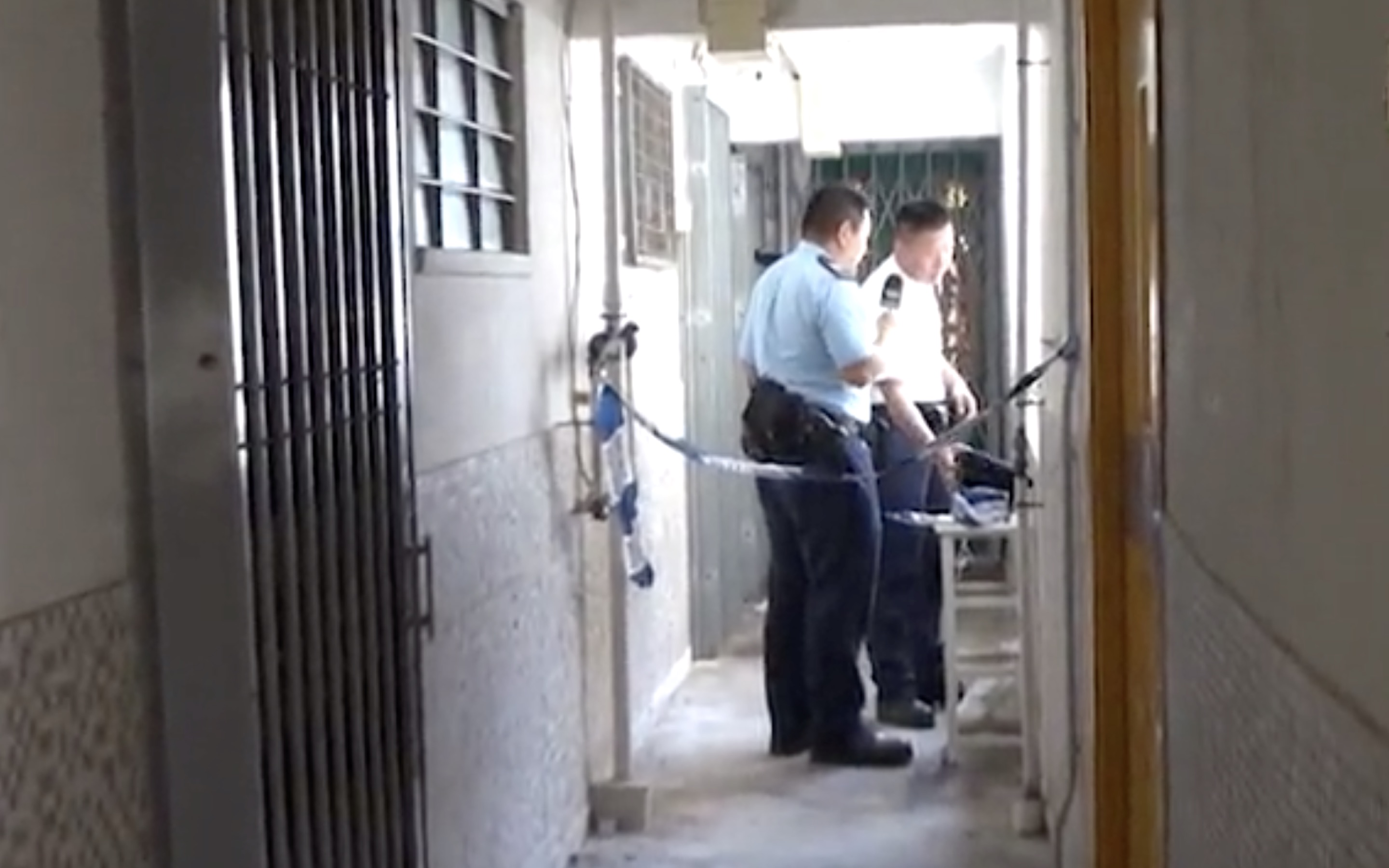 Police cordon off the apartment where a woman reportedly ran away from her boyfriend after he poured kerosene over her and threatened to burn her alive. Screengrab via Apple Daily video.