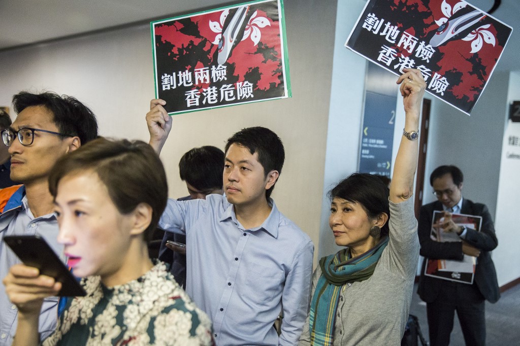 Pro-democracy lawmaker Ted Hui (center) holds a sign protesting a proposal to allow mainland police at West Kowloon Station at a press conference at the Legislative Council building last year. Photo via AFP.