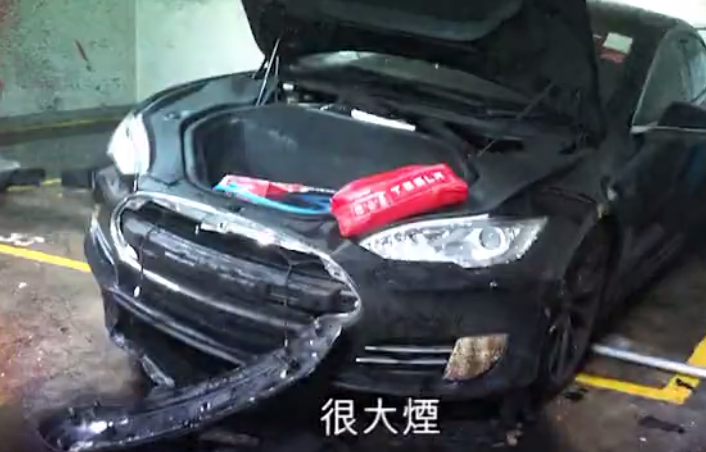 A Tesla Model S that apparently spontaneously caught fire in a Hong Kong parking lot in mid May. Screengrab via Apple Daily video.
