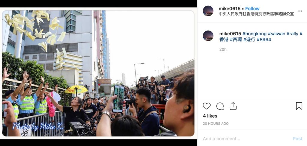 Police officers react as an activist tosses fake money in front of the Liaison Office of the Central People's Government on Sunday. Photo via Instagram.