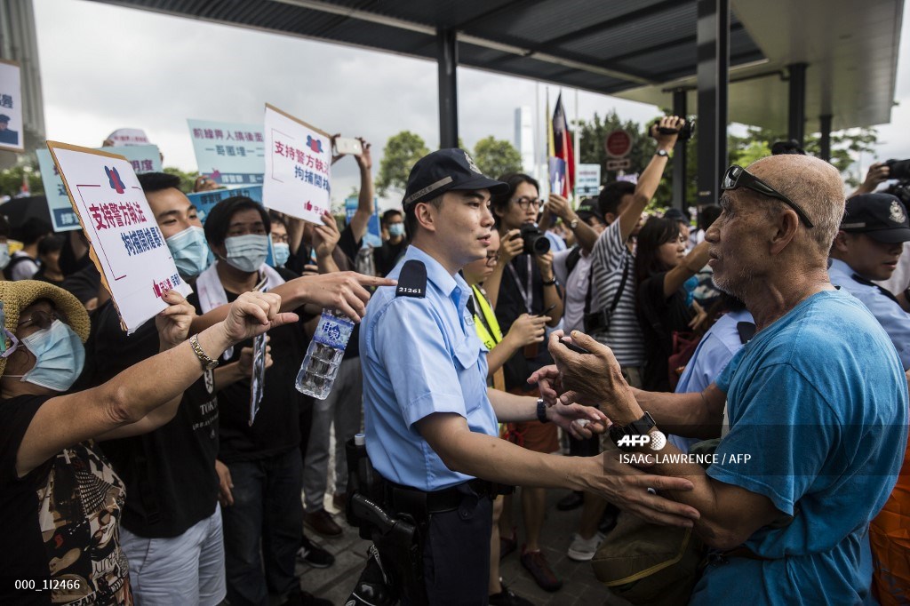 A police officer (C) separates pro-democracy protesters (L) and a pro-Beijing (R) supporter during a rally in support of police in Hong Kong on June 30, 2019. – The international finance hub witnessed the worst political violence in a generation as police fought largely young demonstrators opposed to a now postponed plan to allow extraditions to the Chinese mainland. (Photo by ISAAC LAWRENCE / AFP)
