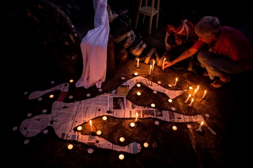 A Catholic devotee and her grandchild lights a candle beside mock chalk figure representing an extra judicial killing victim during a prayer rally condemning the government’s War on Drugs in Manila on February 22, 2017. (Photo: Noel Celis/AFP)