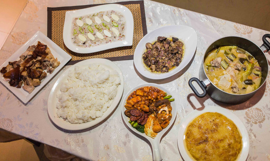 A spread of Filipino food: pork sinigang, chicken liver and gizzard adobo, milk fish kinilaw, lechon, beef puchero, pinaso dessert, and rice. Photo: Jacques Manuntag/Coconuts