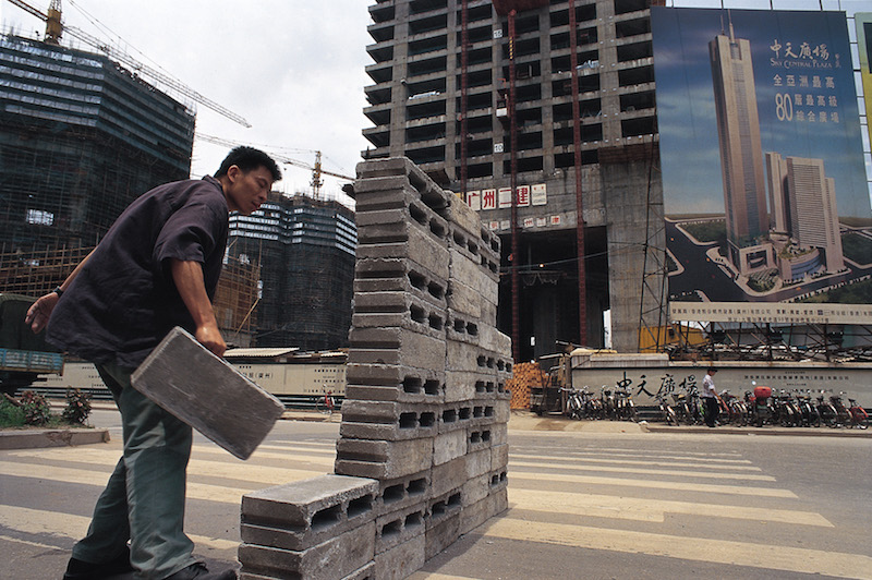 'Safely Maneuvering Across Lin He Road' by Lin Yilin. This site-specific performance involved building a wall of concrete blocks and moving from one side of a busy road in central Guangzhou to another. The performance interrupted traffic for 90 minutes, and symbolized the rapid redevelopment of China. Photo: Lin Yilin and Boers-Li Gallery