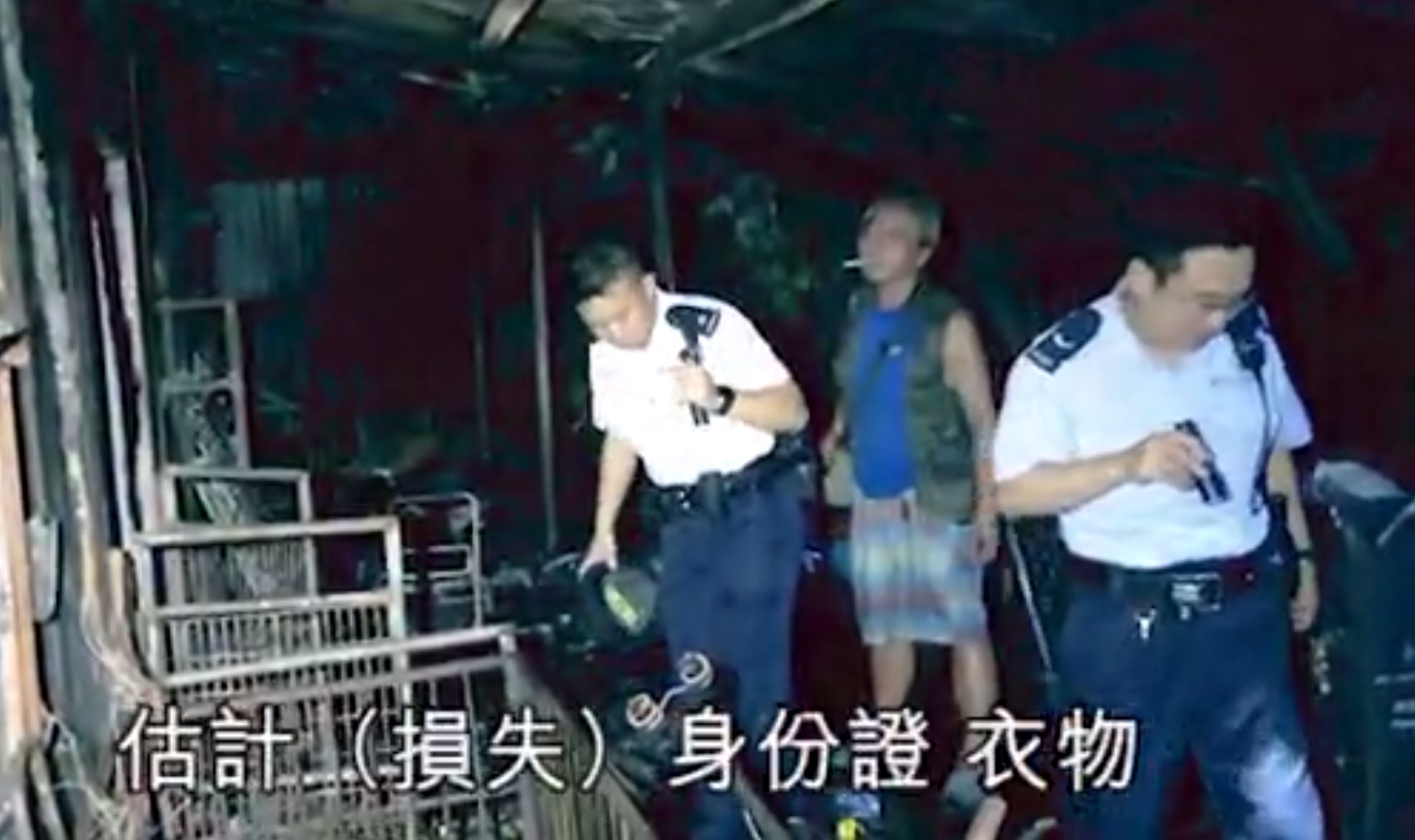 Authorities and the homeowner inspect the scene of a house fire in Tuen Mun believed to be caused by an exploding power bank that had been left to charge. Screengrab via Apple Daily.