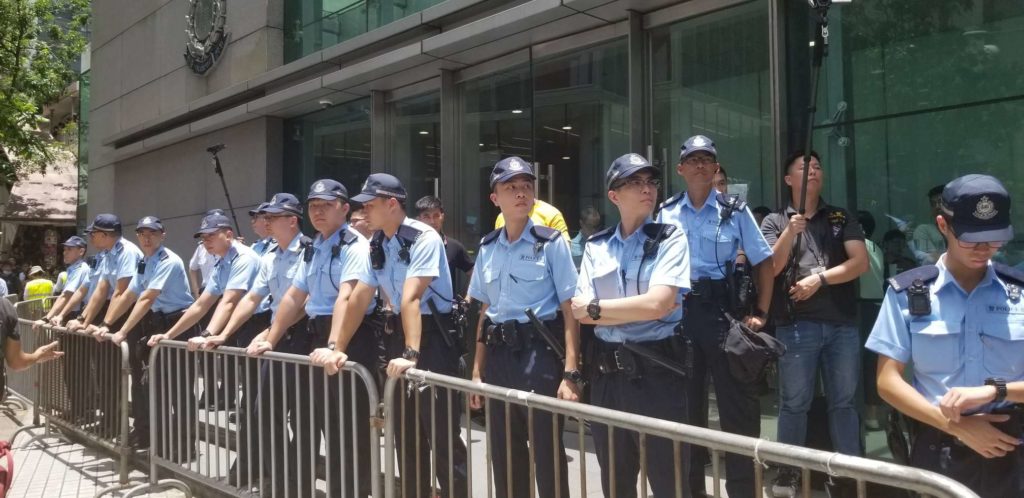 Officers stand guard at police headquarters as anti-extradition protesters surround the building. Photo by Vicky Wong.