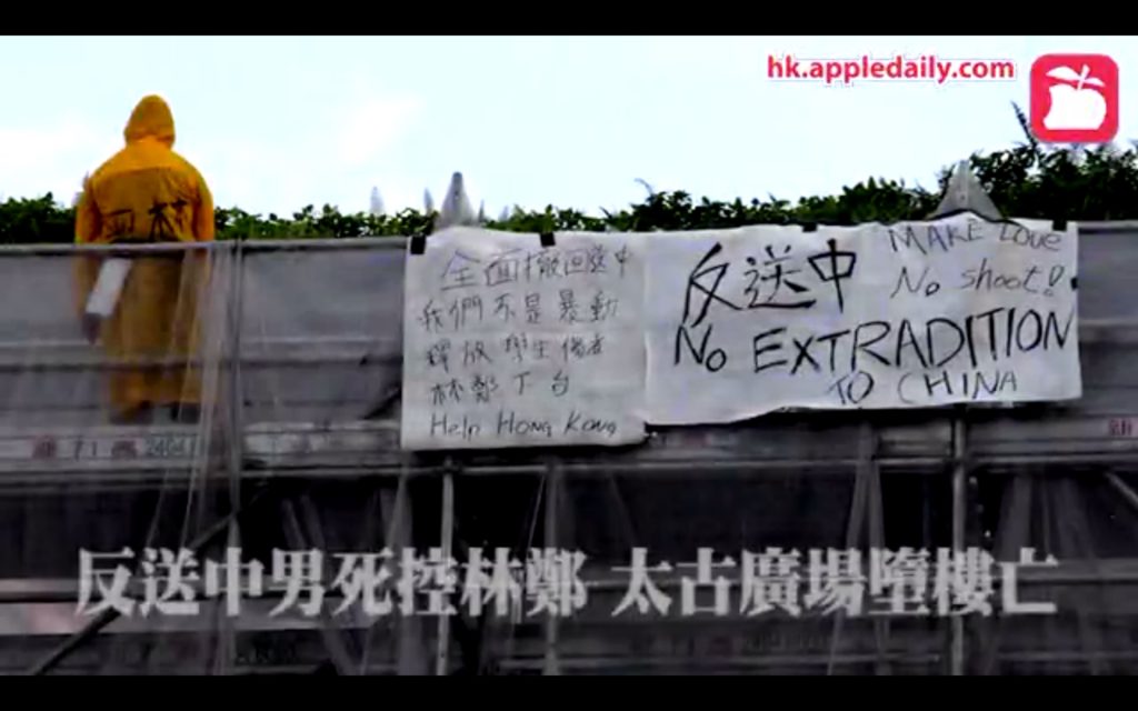 An anti-extradition bill protester stands on a set of scaffolding outside Pacific Place, shortly before falling to his death. Screengrab via Apple Daily video.
