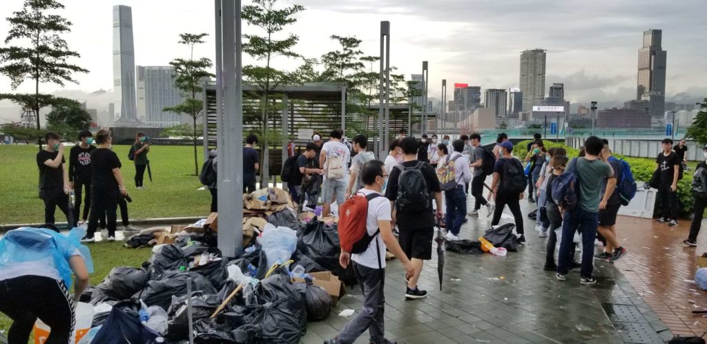 Protesters cleaning up trash at Tamar Park left over from yesterday's protest against the extradition bill. Photo by Vicky Wong.