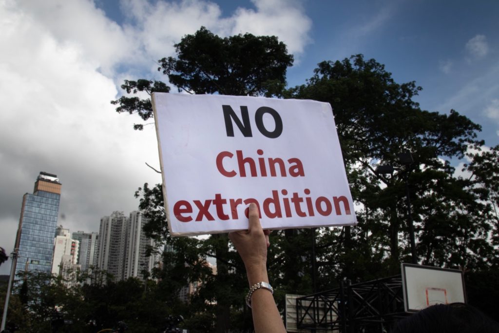 A protester brandishes a sign at the enormous anti-extradition march today. Photo by Samantha Mei Topp.