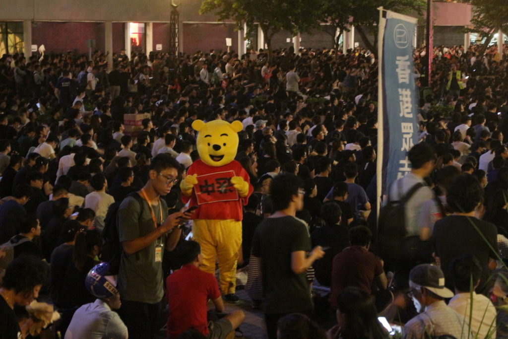 A protester dressed as Winnie the Pooh, a common reference to Xi Jinping, wanders the crowd at tonight's protest. Photo by Vicky Wong.