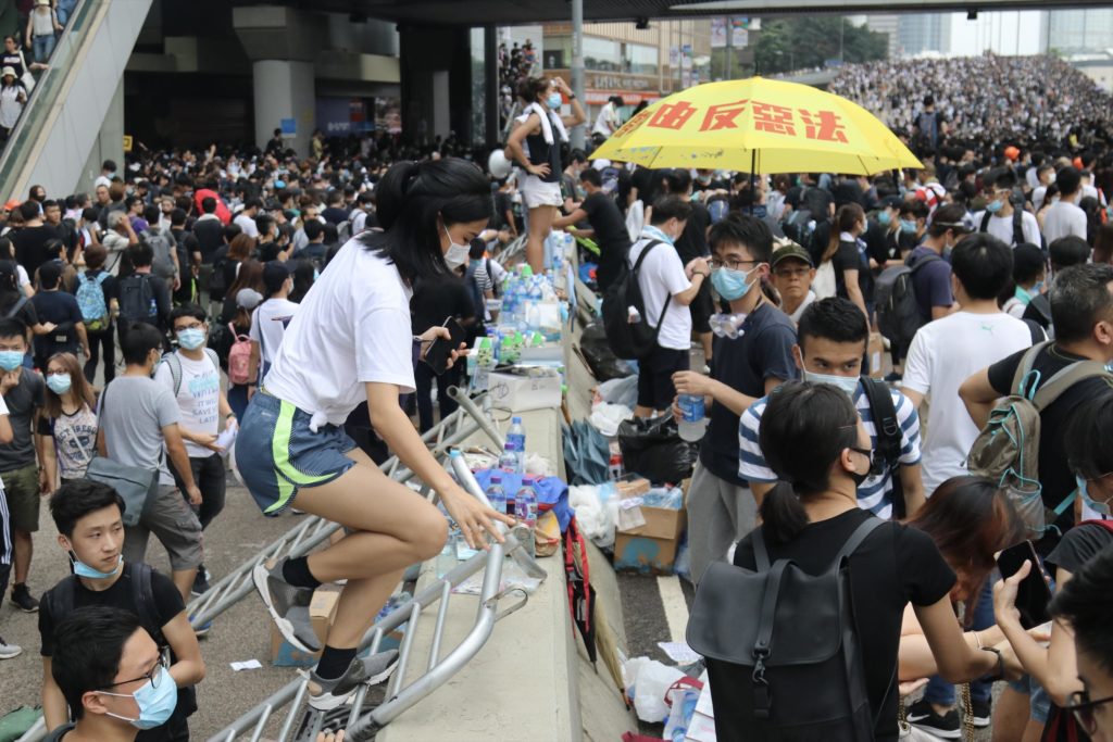 Protesters helping others climb up railing that has been converted into a makeshift ladder at a demonstration against a controversial extradition bill on Wednesday, June 12 2019. Photo by Samantha Mei Topp.