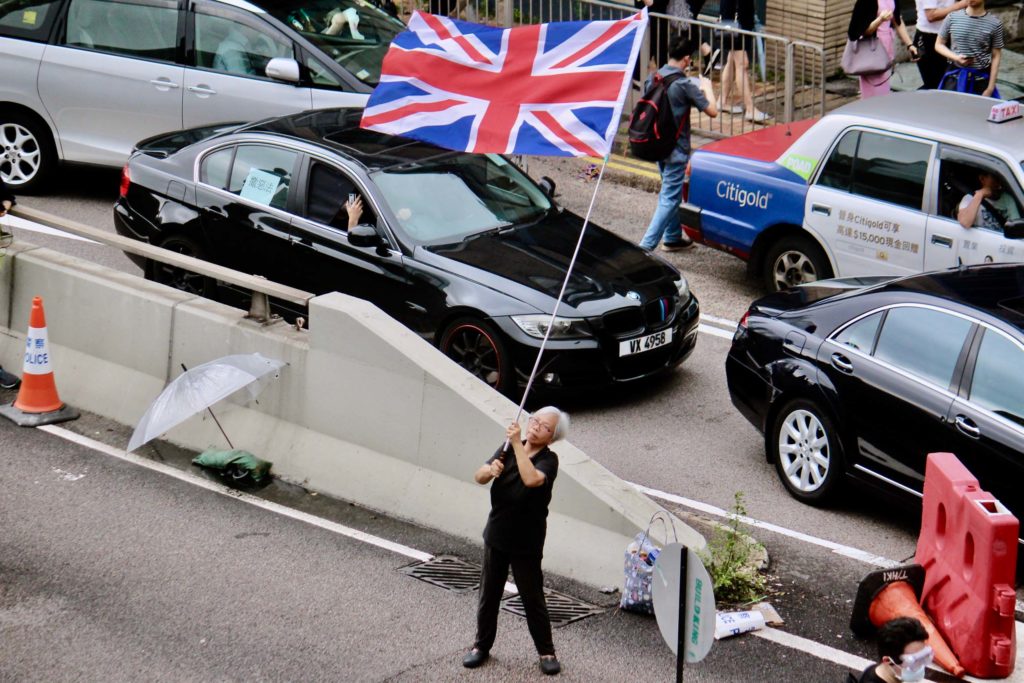 A female protester waves the Union Jack flag on Connaught Road Central during an extradition bill protest. Photo by Vicky Wong.