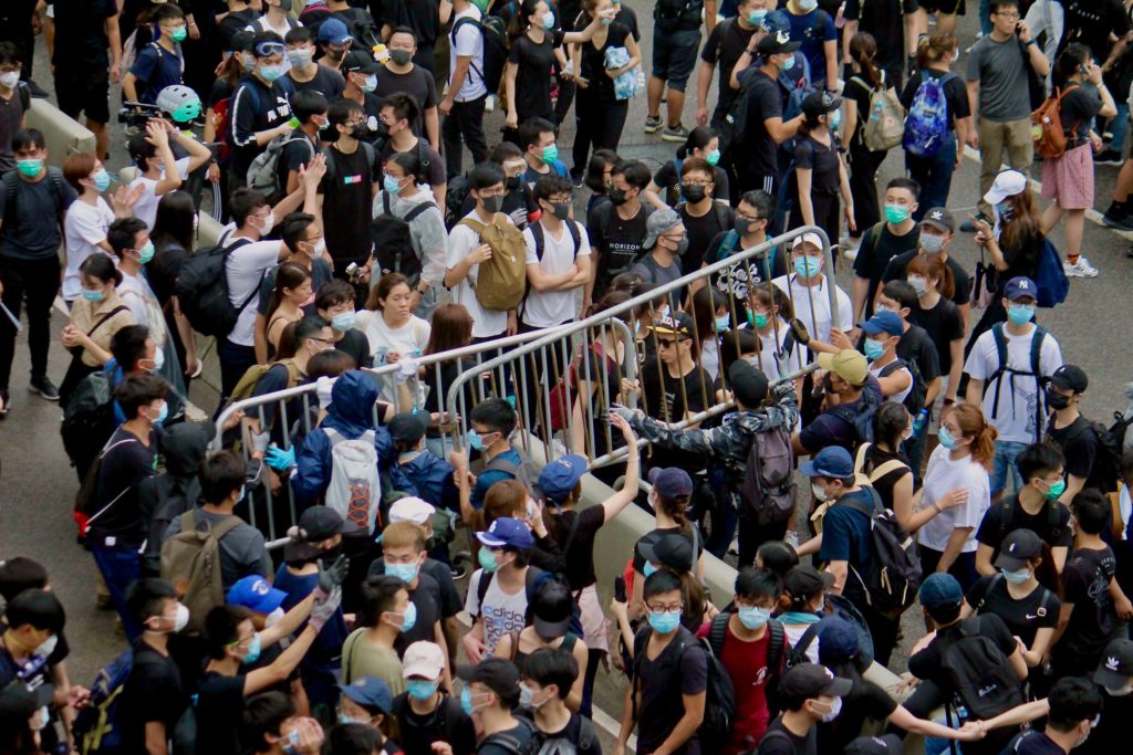 Protesters moving a metal fence in order to build barriers protecting themselves from police during a protest against a controversial extradition bill. Photo by Vicky Wong.