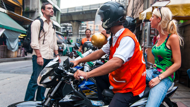 A Bangkok moto-taxi driver picks up a woman in Bangkok’s Nana area. Photo:  Mark Fischer / Flickr