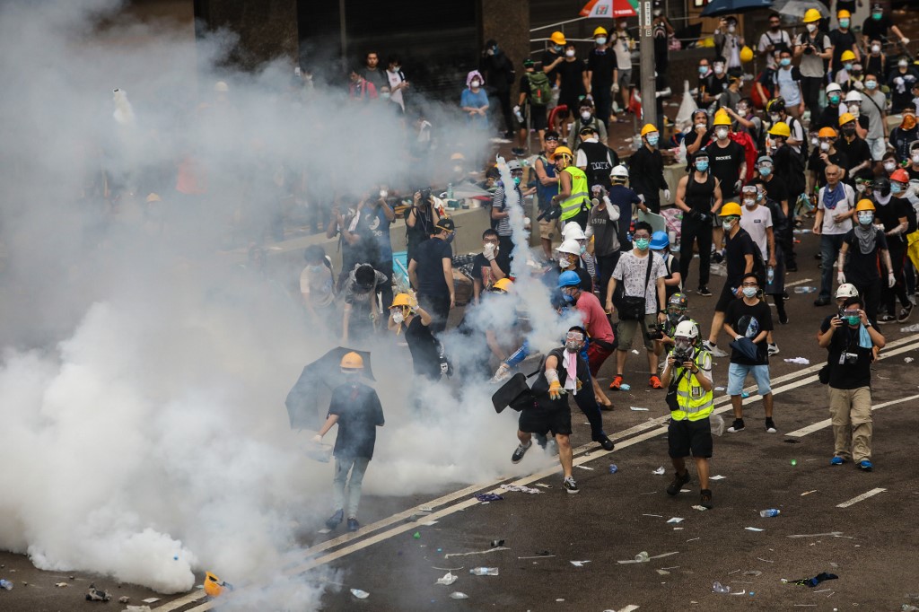 A protester throws a tear gas canister fired by police during a rally against a controversial extradition law proposal outside the government headquarters in Hong Kong on June 12. Photo via AFP.