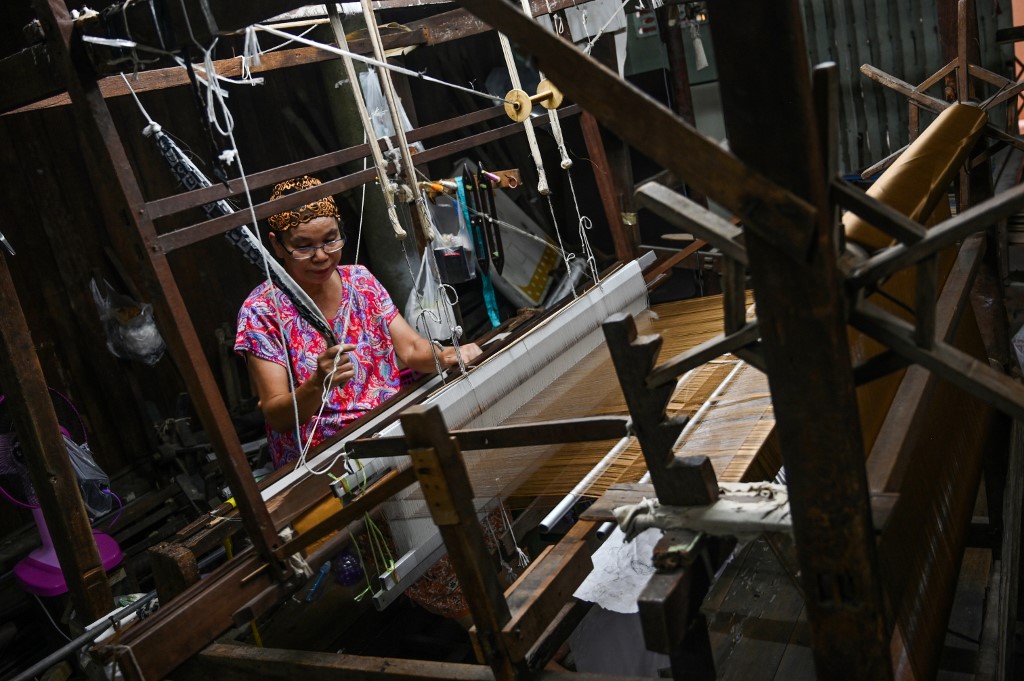 This photo taken on May 22, 2019 shows Rampai Sripetch, a 65-year-old Thai Muslim woman, weaving silk fabric on a loom at a workshop near Darul Falah mosque in Bangkok. Photo by Romeo Gacad / AFP