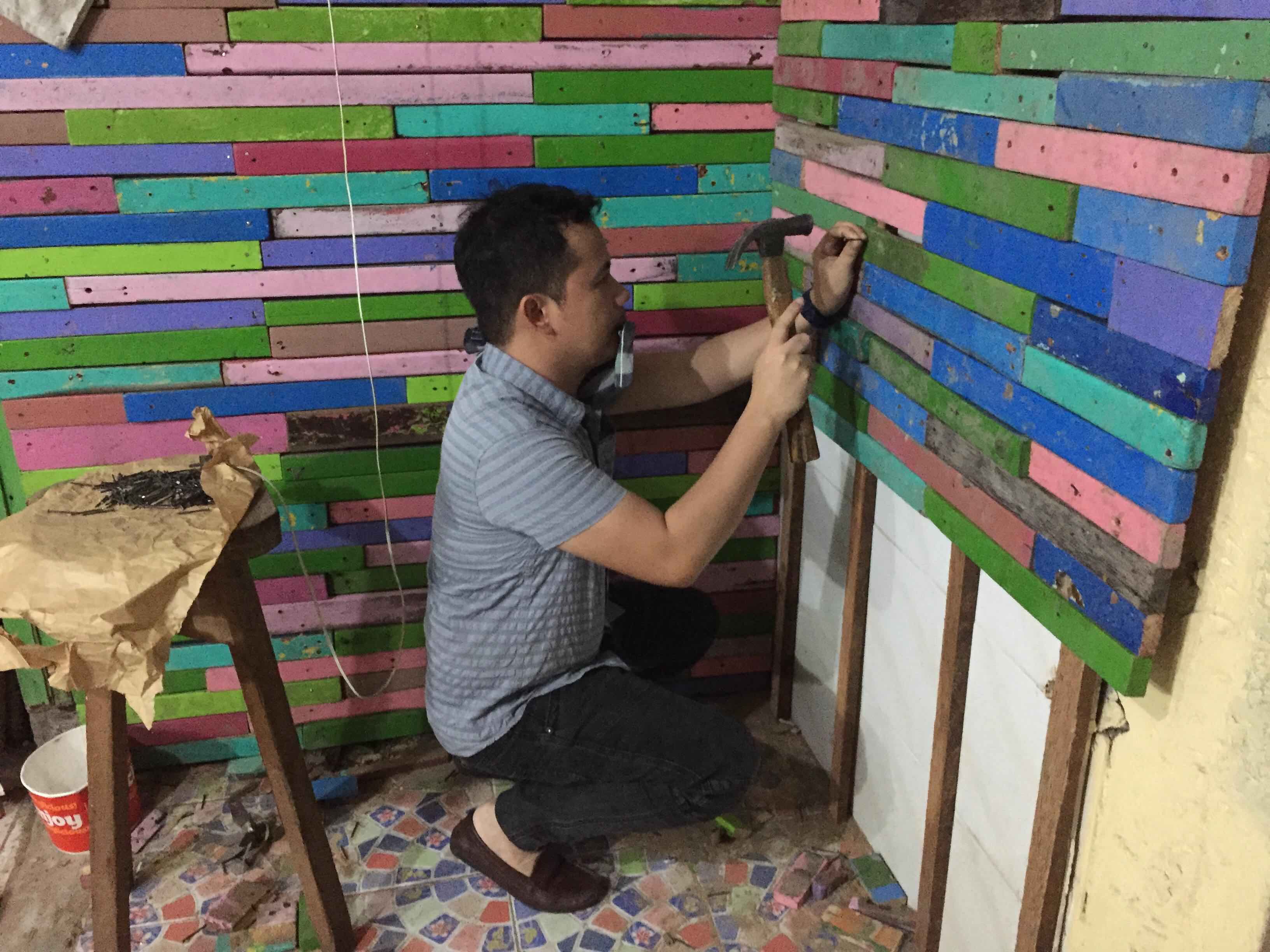 The teacher attaching the pieces of wood to the wall. (Photo: Reynel Calmerin)