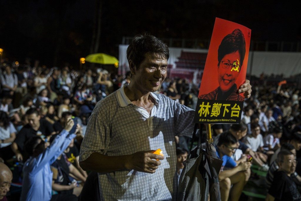 A man holds a poster, showing Hong Kong Chief Executive Carrie Lam, against the proposed extradition law at last night's vigil. Photo via AFP.